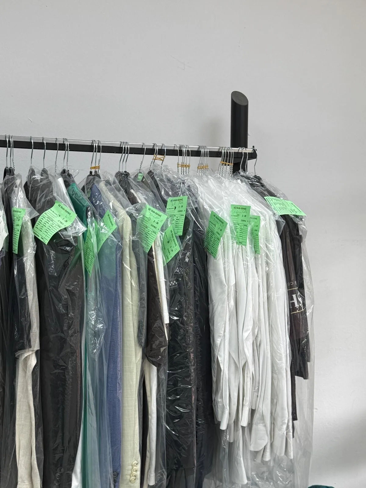Gestoomde kleding hangt beschermd en gelabeld klaar bij Memode in Rijswijk